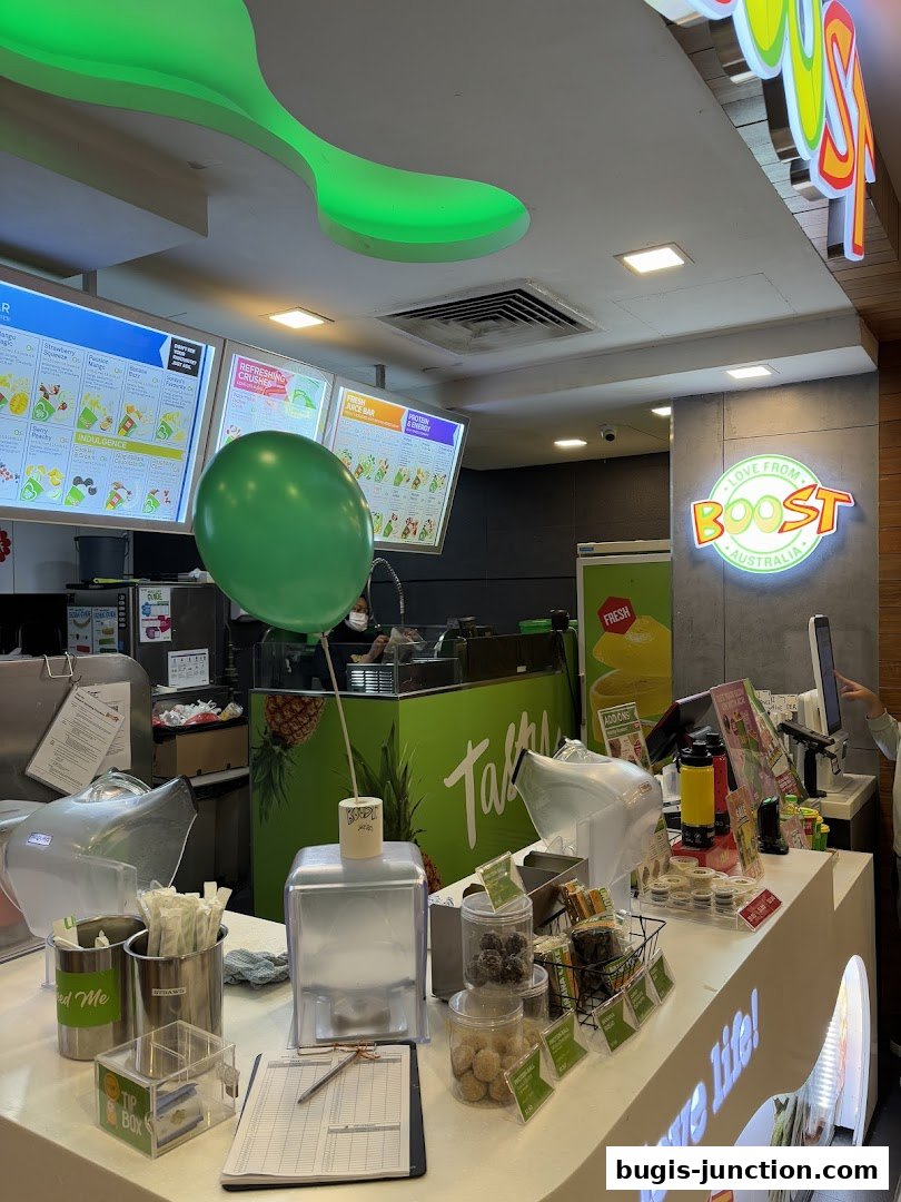 Interior view of a Boost Juice shop with a counter, menu boards, and a green balloon.