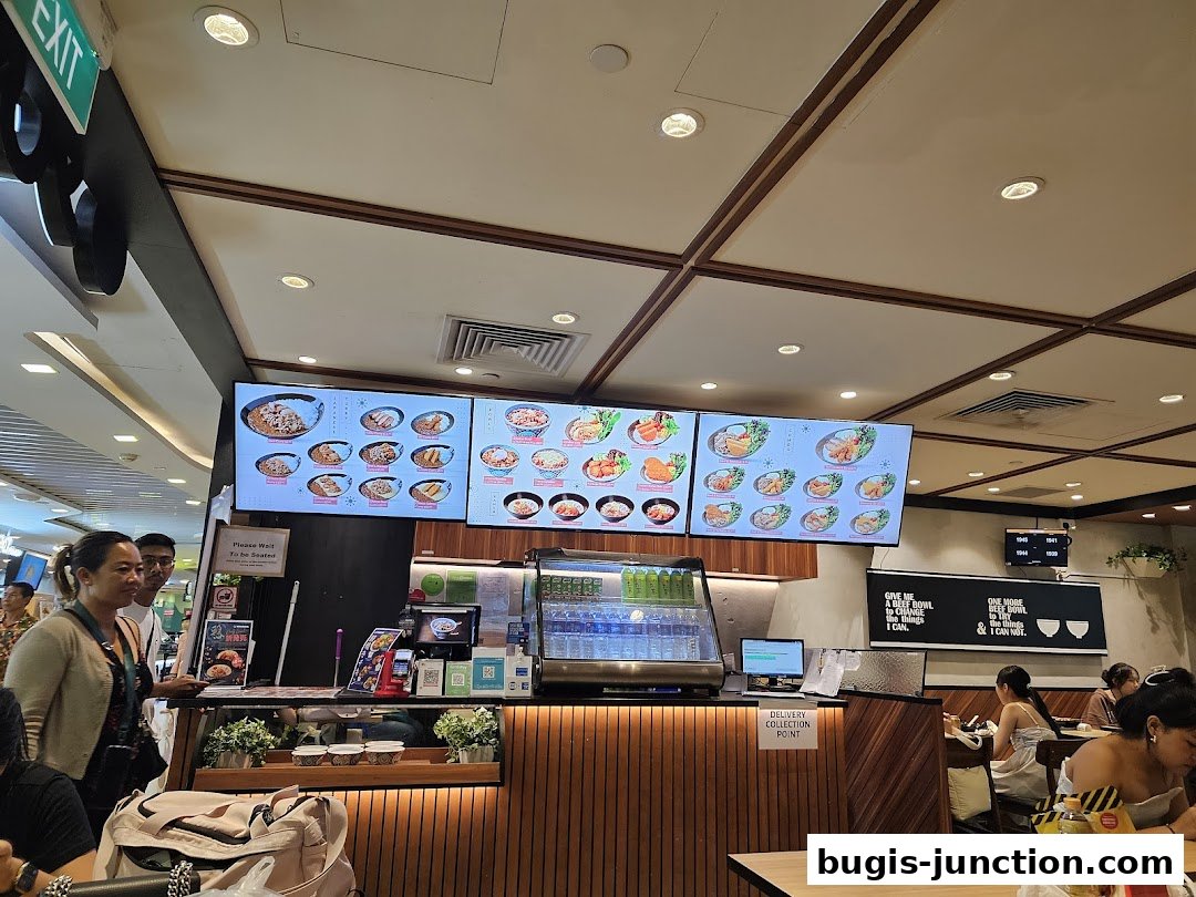 Interior view of Yoshinoya restaurant with digital menu boards and customers dining.