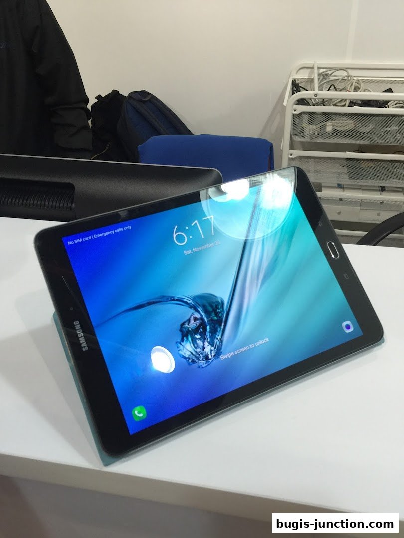 A Samsung tablet is displayed on a white surface, showing the lock screen.