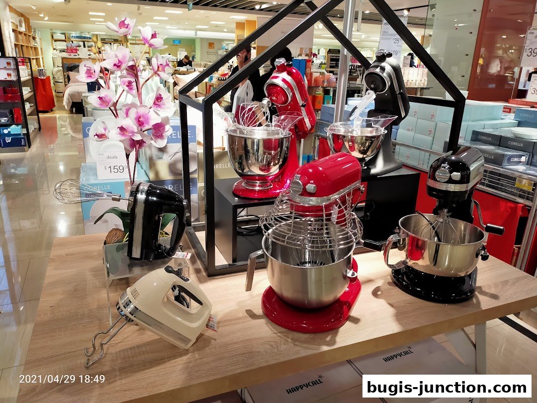 A display of various stand mixers and hand mixers on a wooden table.