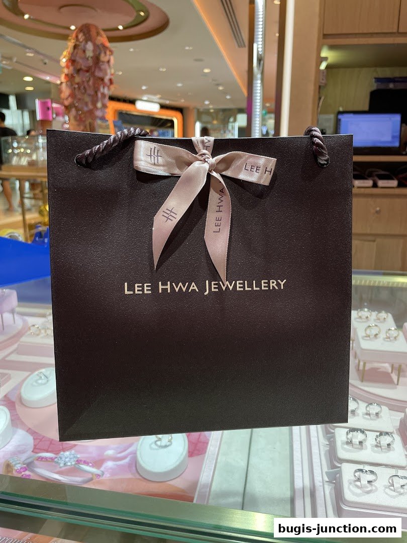 A dark brown shopping bag from Lee Hwa Jewellery with a ribbon bow.