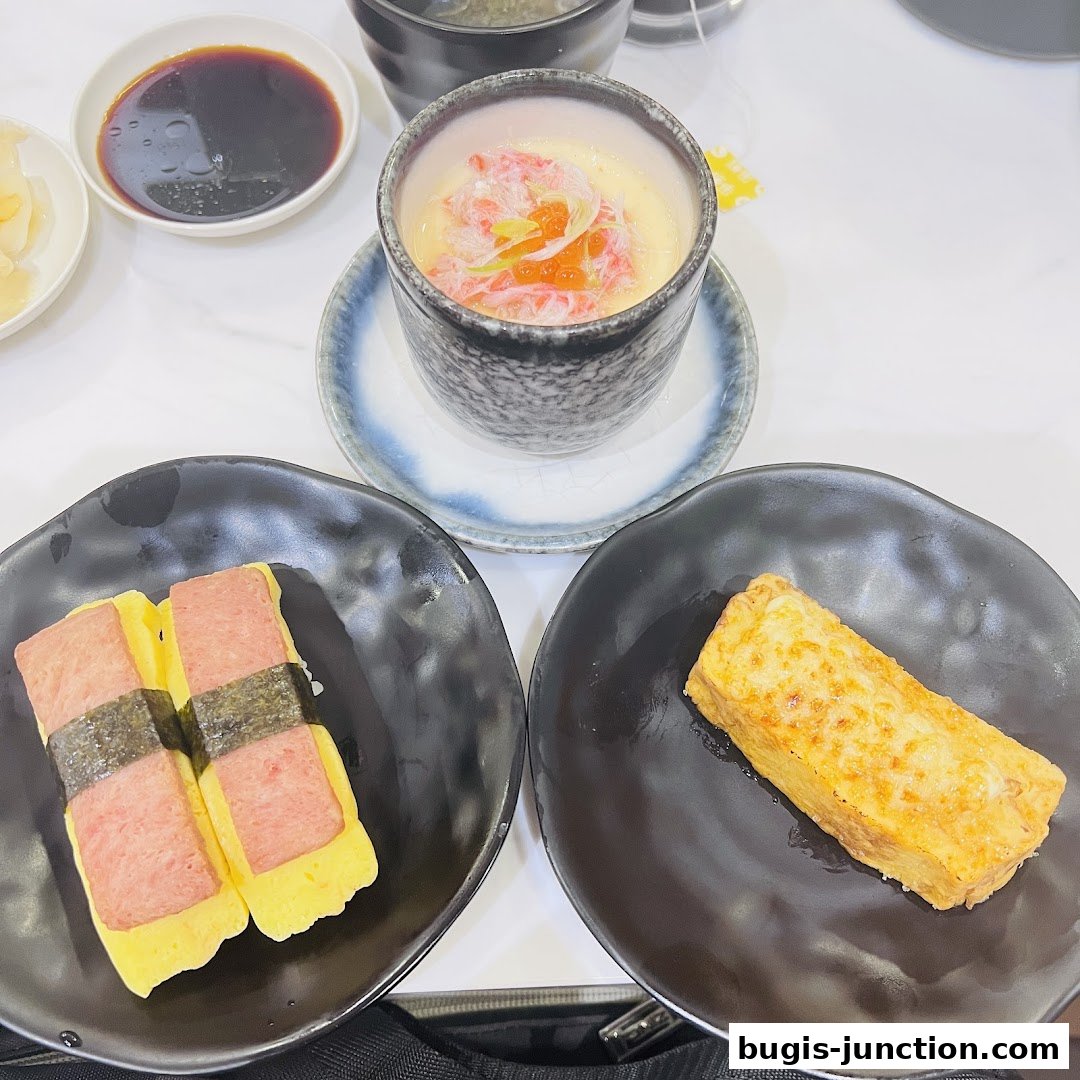 A close-up of Japanese dishes including chawanmushi, tamagoyaki, and spam sushi.