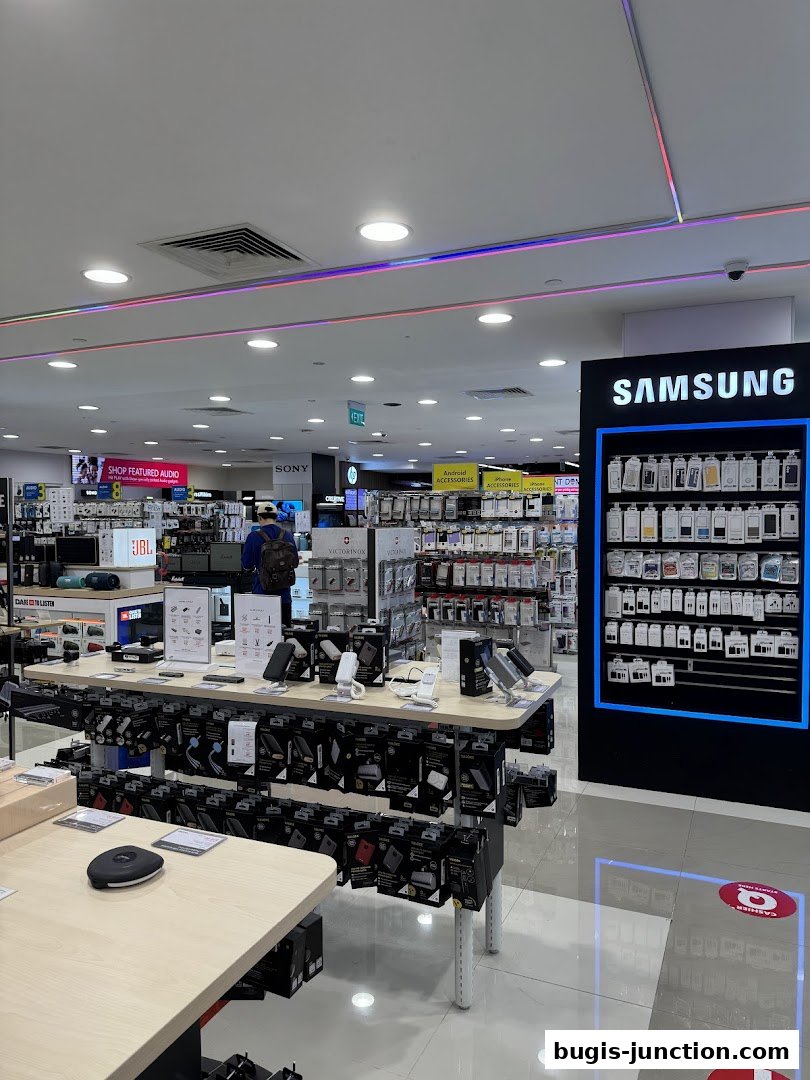 Interior view of a modern electronics store with displays of mobile accessories and Samsung products.