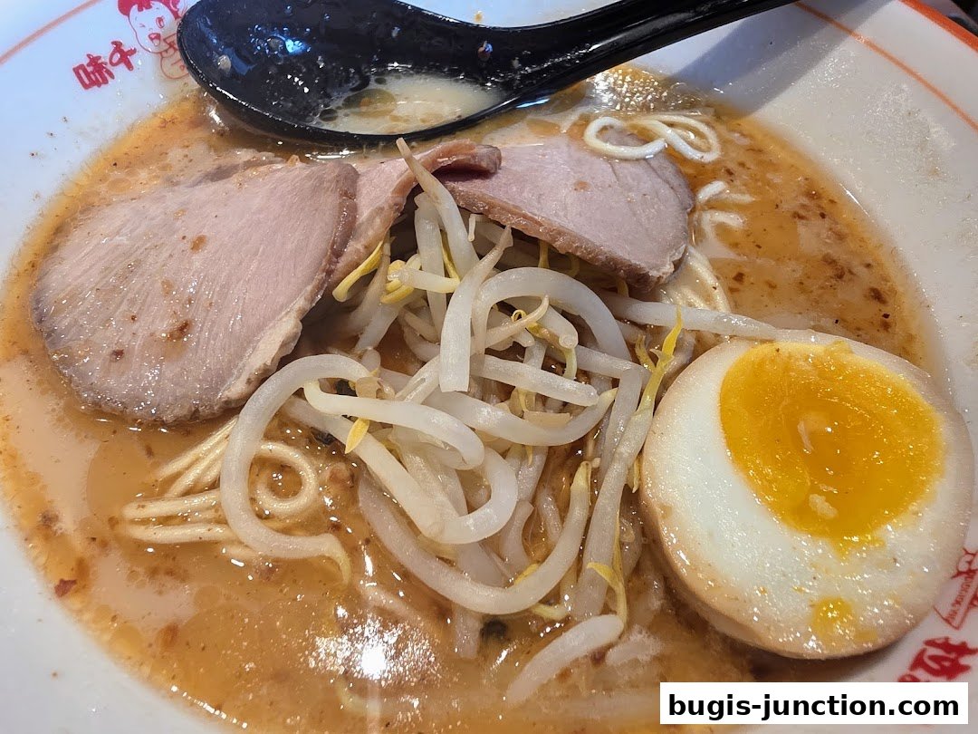 A close-up of a delicious bowl of Ajisen Ramen with tender pork, bean sprouts, and a perfectly cooked egg.