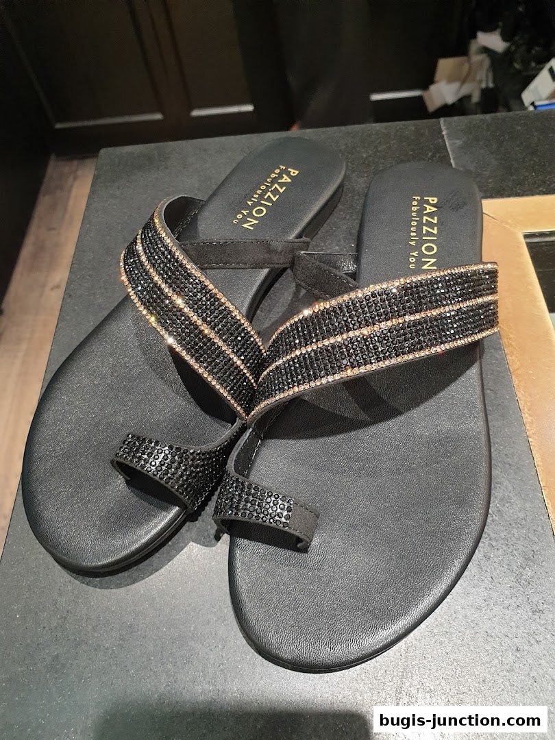 A pair of black flat sandals with sparkling crystal embellishments on the straps.