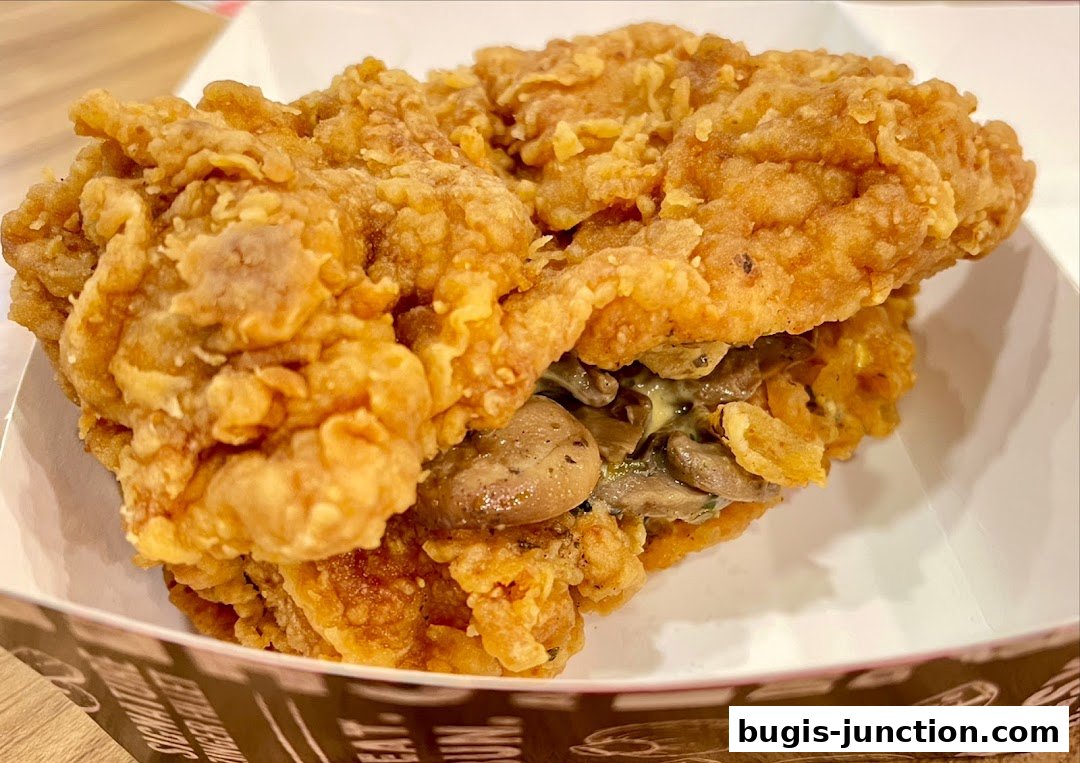 A close-up of a crispy fried chicken sandwich with mushrooms and creamy sauce.