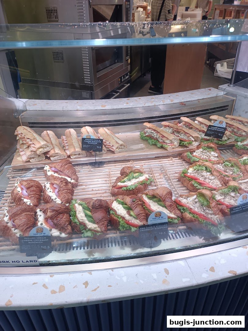 A display case filled with various sandwiches and croissants at Paris Baguette.