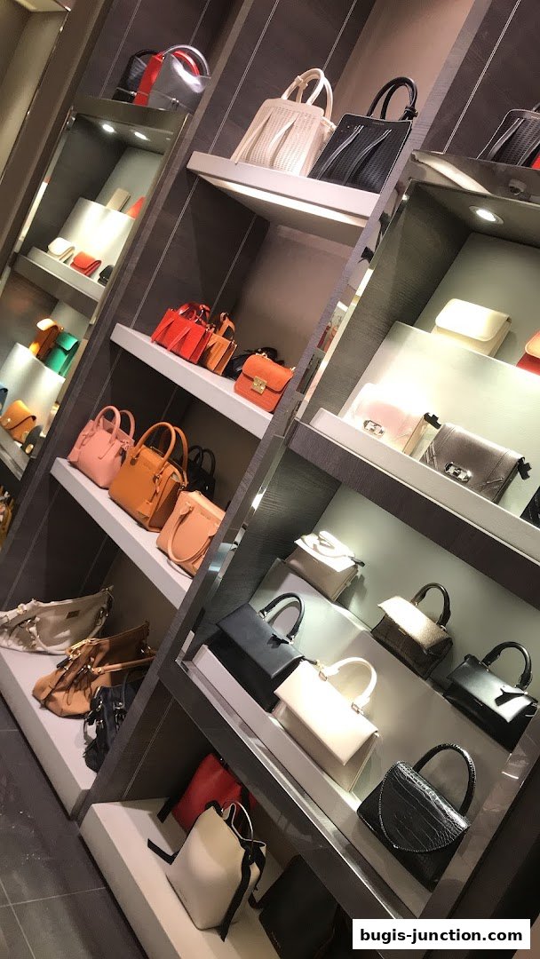 A display of various CHARLES & KEITH handbags in different colors and styles on shelves.