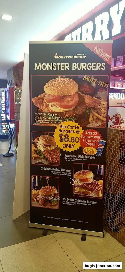 A promotional stand for Monster Curry featuring various burger options and prices.