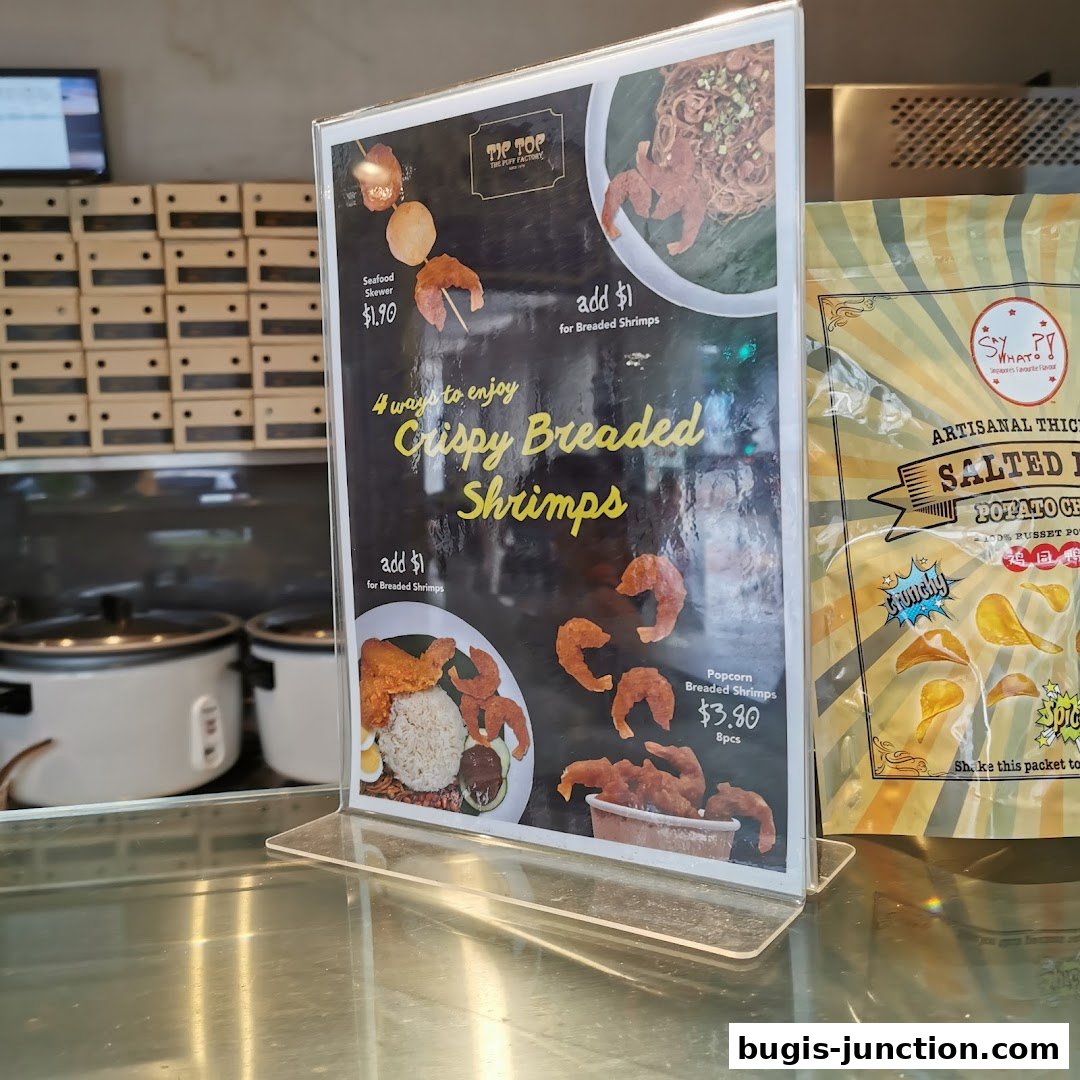 A menu board showcasing crispy breaded shrimps and seafood skewers from Tip Top Curry Puff.