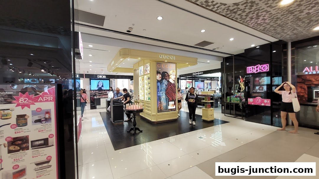 A view of a shopping mall interior with various luxury brand stores and displays.