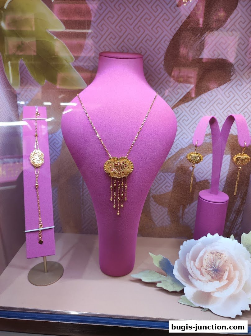 A display of elegant gold jewelry, including a necklace, bracelet, and earrings, on pink mannequins.