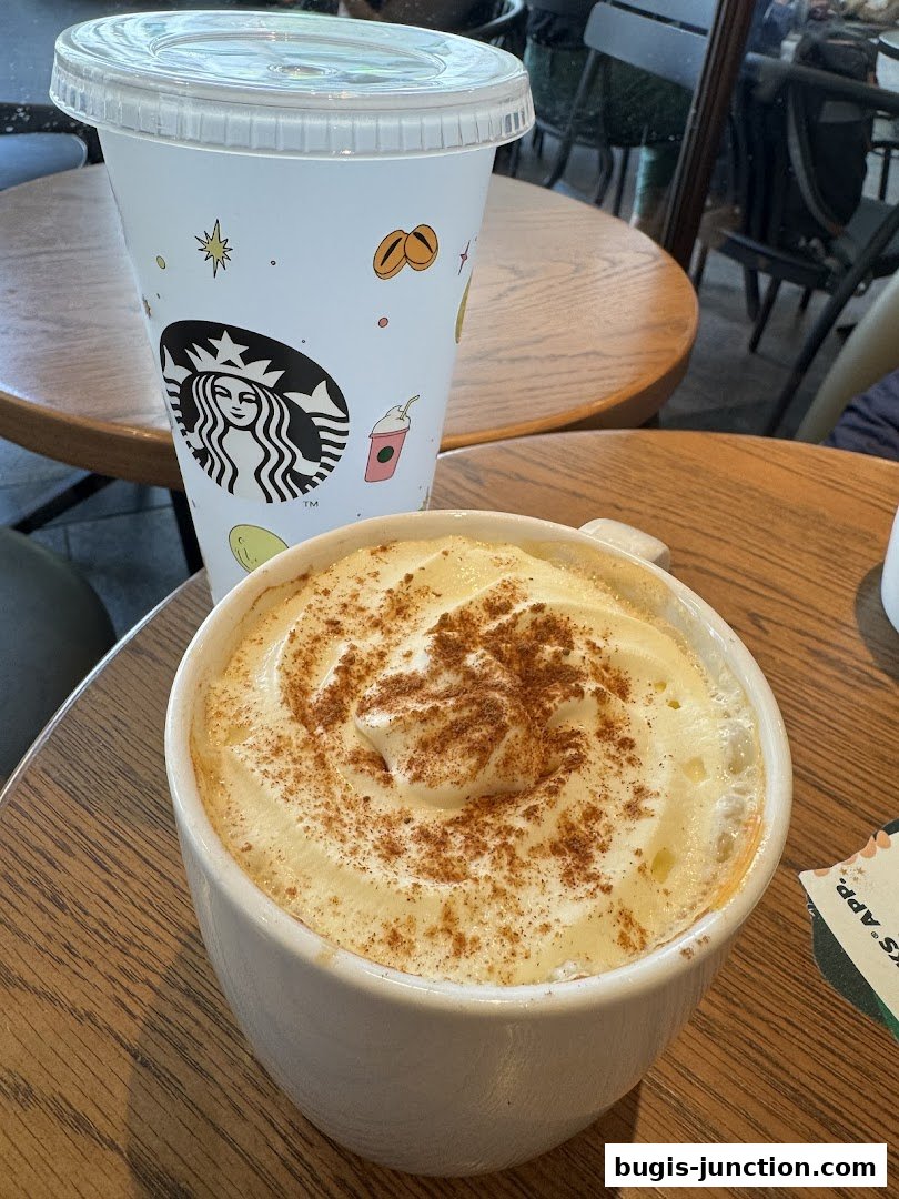A close-up of a Starbucks drink with whipped cream and cinnamon, next to a branded cup.