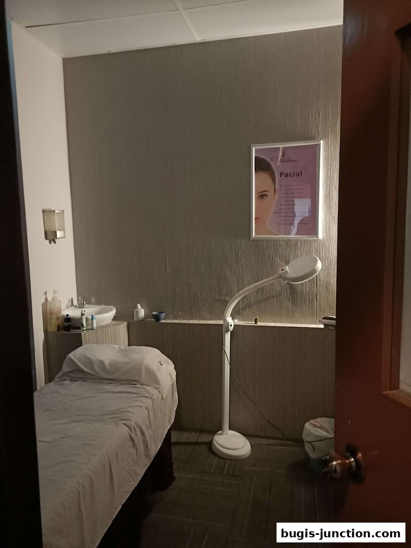 A treatment room with a massage bed, sink, and facial lamp.