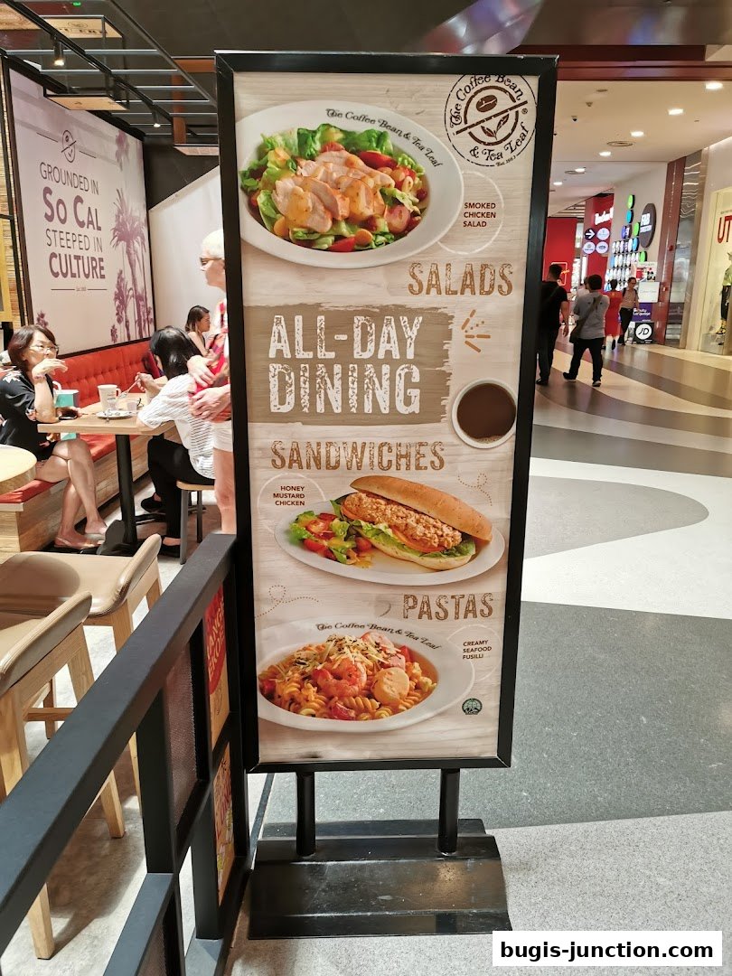 A sign advertising The Coffee Bean & Tea Leaf's all-day dining menu, featuring salads, sandwiches, and pastas.