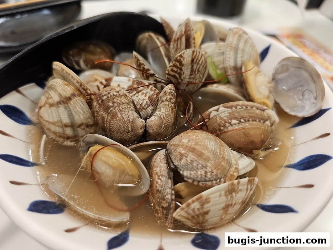 A close-up shot of a bowl filled with steamed clams in a savory broth.
