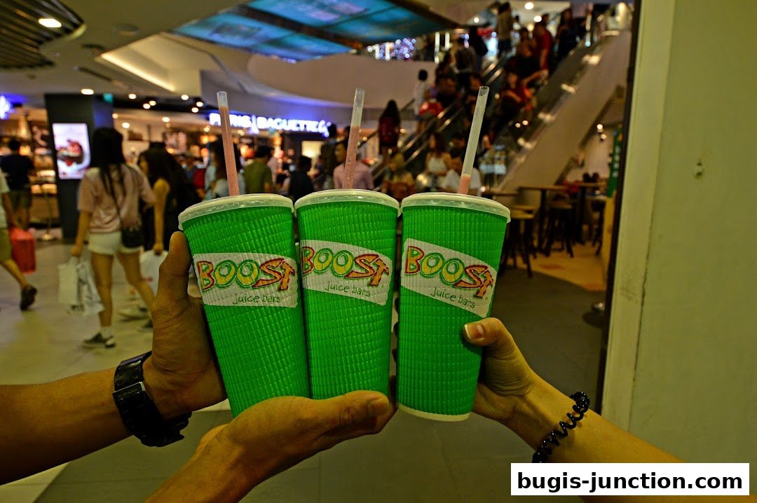 Three green cups with Boost Juice branding are held up in a toast.