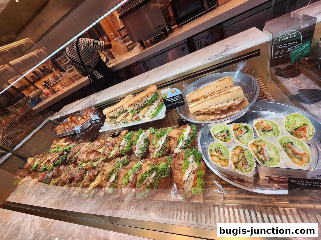 A display case filled with various sandwiches, croissants, and wraps at Paris Baguette.