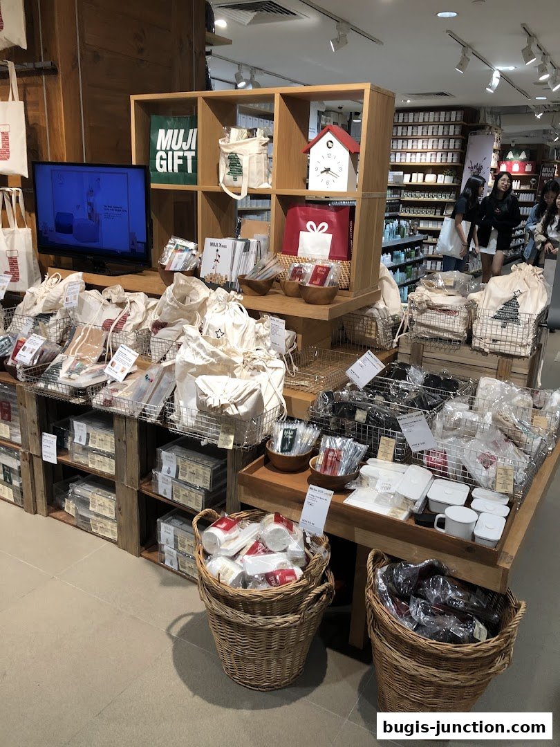 A display of MUJI products including tote bags, stationery, and home goods.