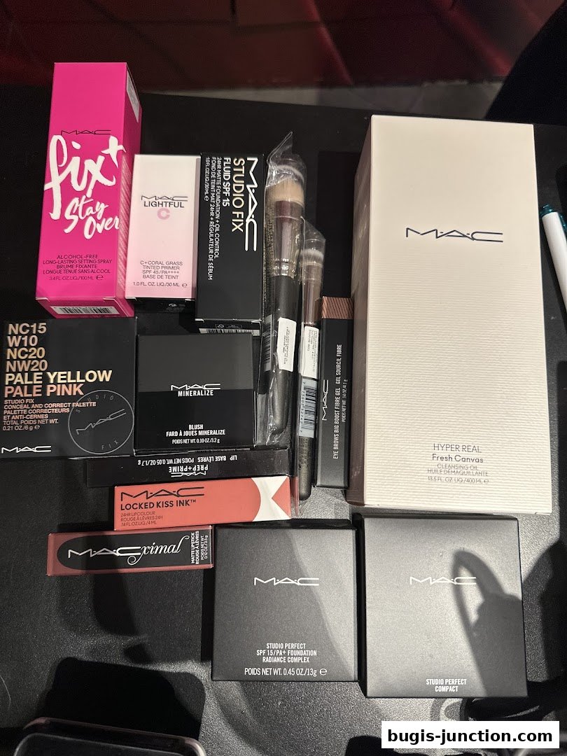 A collection of MAC Cosmetics makeup products including foundation, lipstick, blush, and setting spray.