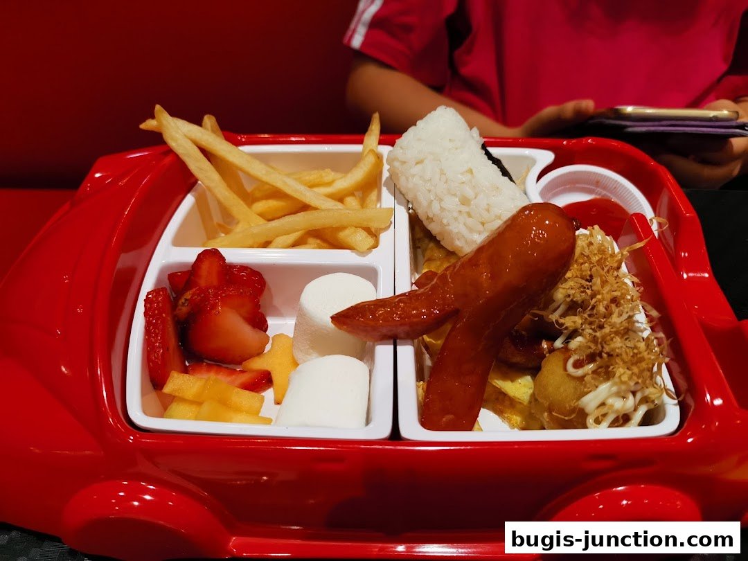 A fun, car-shaped platter filled with a meal including fries, fruit, rice, and sausage.