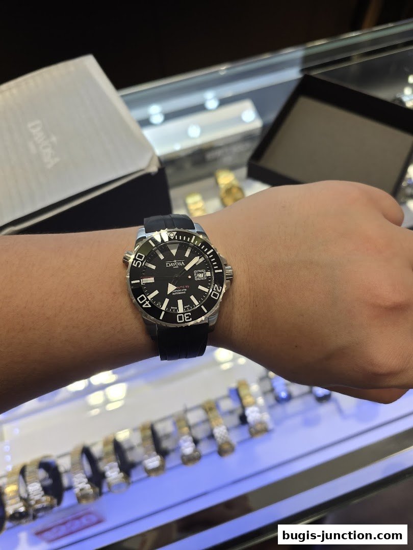 A person wearing a Davosa automatic watch with a black strap in a watch shop.