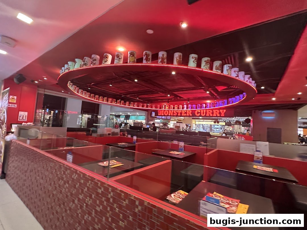 Interior view of Monster Curry restaurant with red booth seating and illuminated signage.