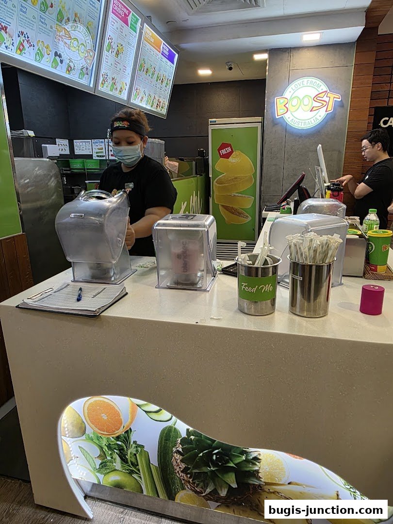 Staff preparing drinks behind the counter at Boost Juice, with menus displayed.