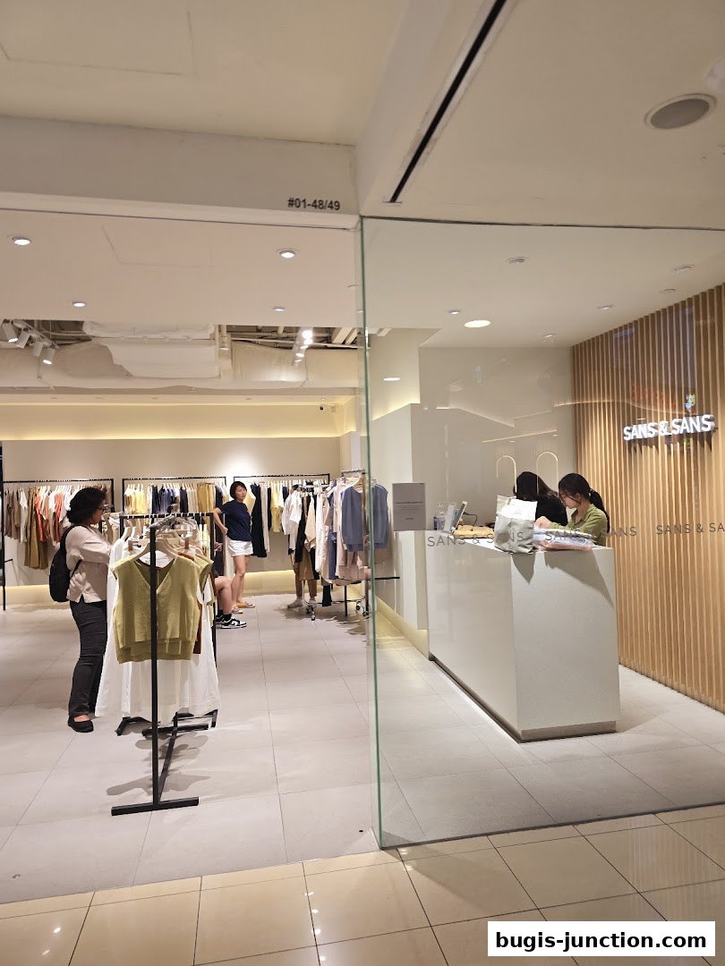 View of the SANS & SANS clothing store entrance with racks of apparel and a checkout counter.