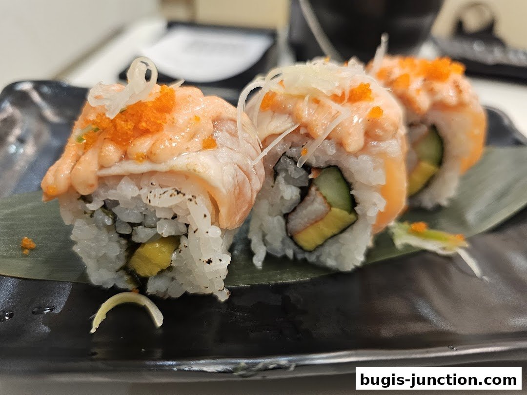 Close-up of delicious sushi rolls with salmon, cucumber, and tobiko on a black plate.
