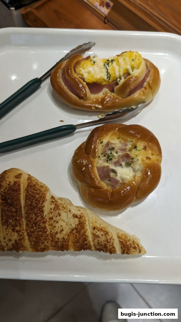 A white tray holding three freshly baked pastries with tongs.