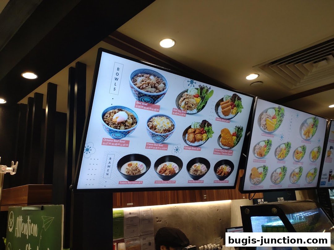 Digital menu boards displaying various Japanese rice bowls and ramen dishes.
