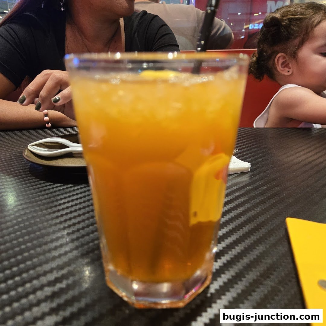 A close-up of a refreshing orange drink with ice, served at a table.