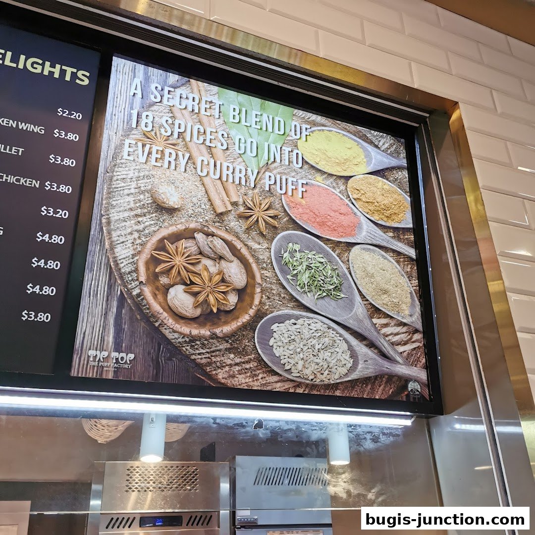 A menu board displaying curry puff flavors and prices, with an image of spices.