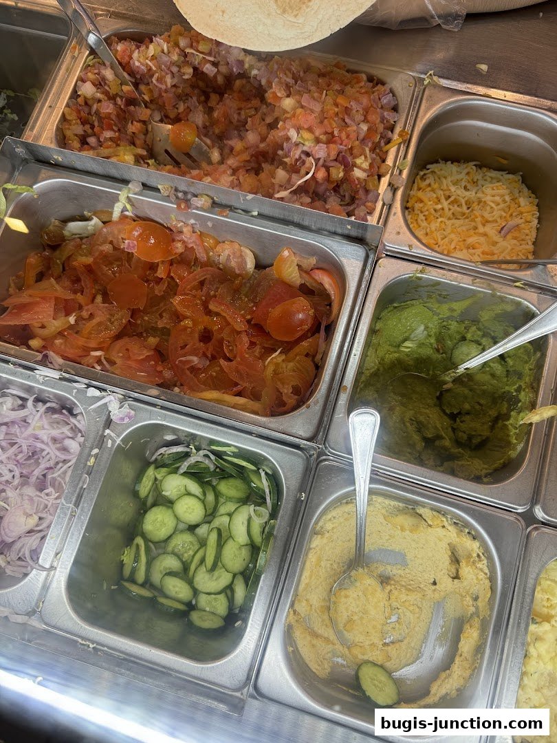 A variety of fresh ingredients for wraps or bowls, including pico de gallo, tomatoes, cucumbers, and guacamole.