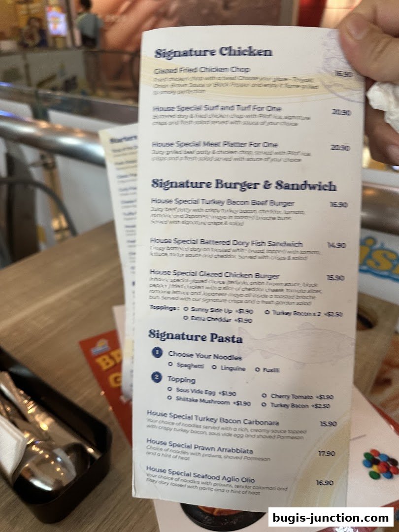 A menu from Big Fish Small Fish Bugis Junction featuring signature chicken, burgers, sandwiches, and pasta dishes.