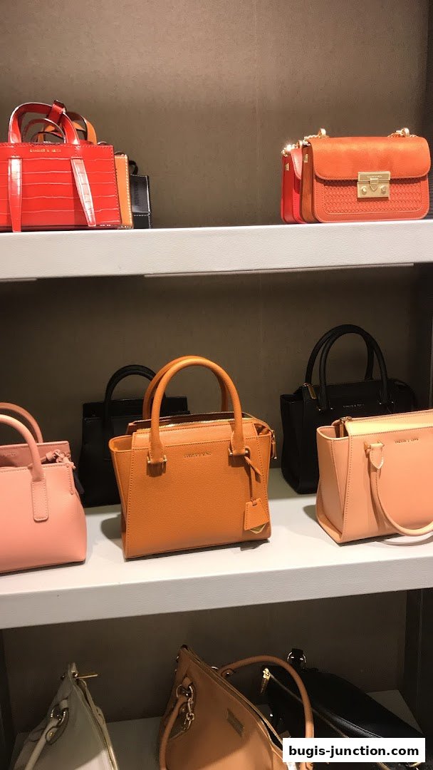 A display of various Charles & Keith handbags in different colors and styles on shelves.