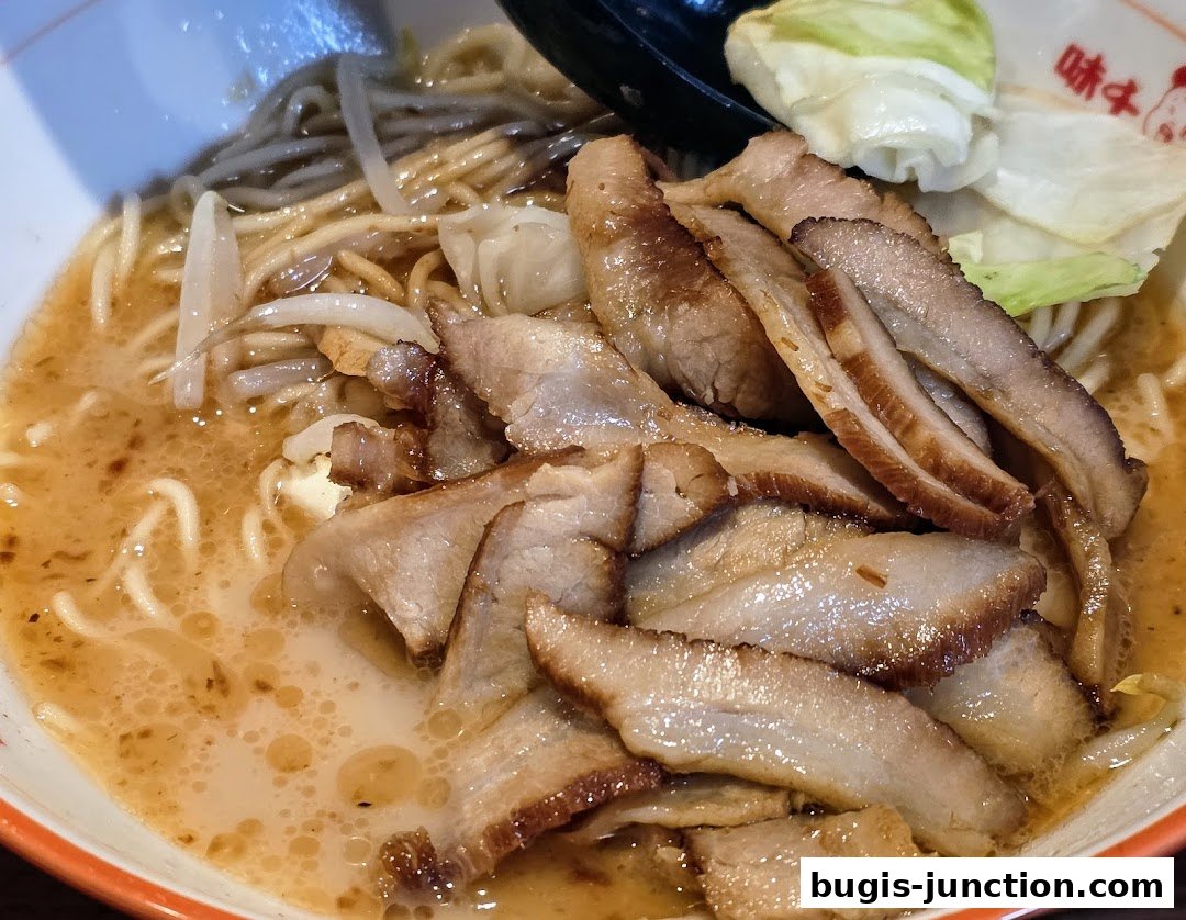 A close-up shot of a delicious bowl of ramen with tender slices of pork and fresh vegetables.