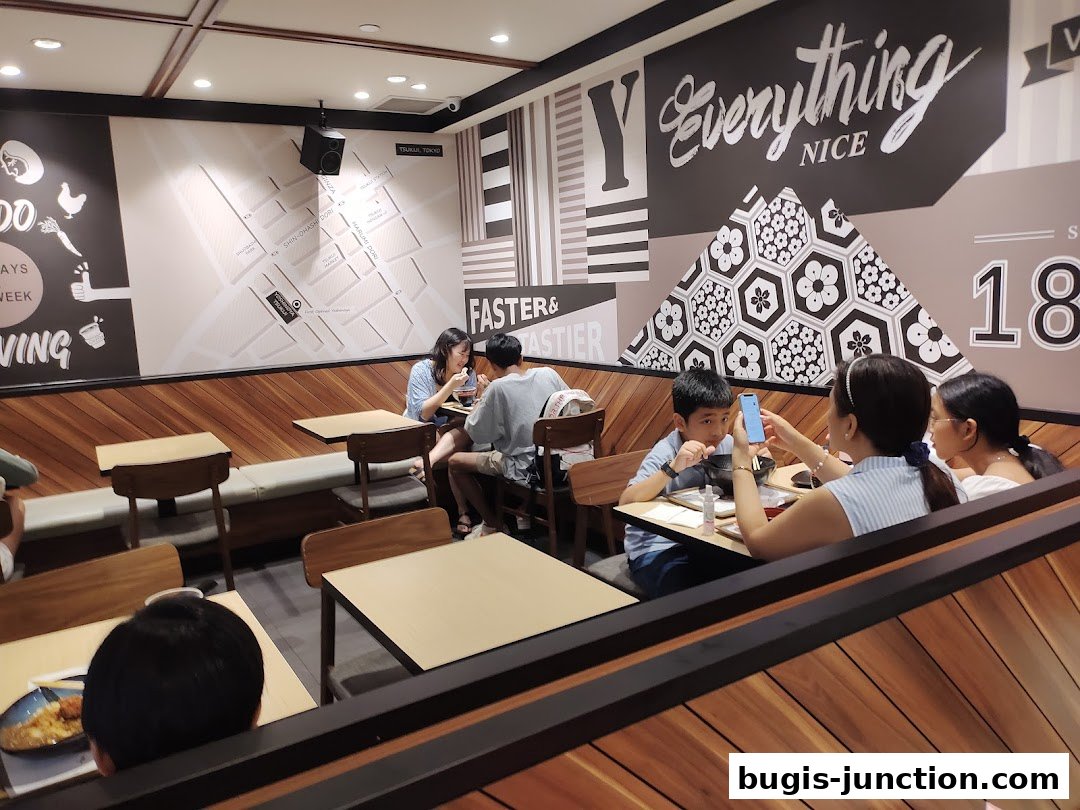 Diners enjoy a meal inside Yoshinoya, a Japanese restaurant with modern decor.
