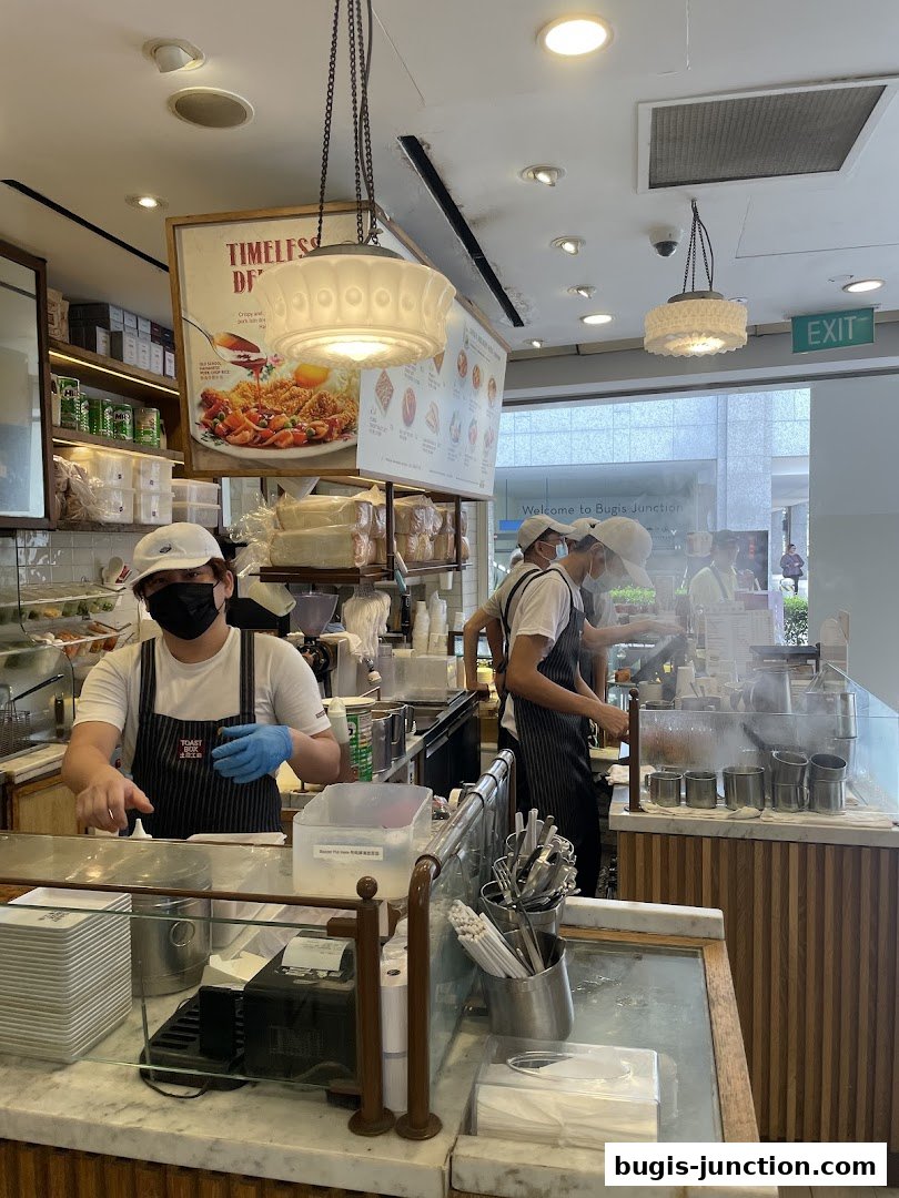 Staff preparing food behind the counter at Toast Box Bugis Junction.