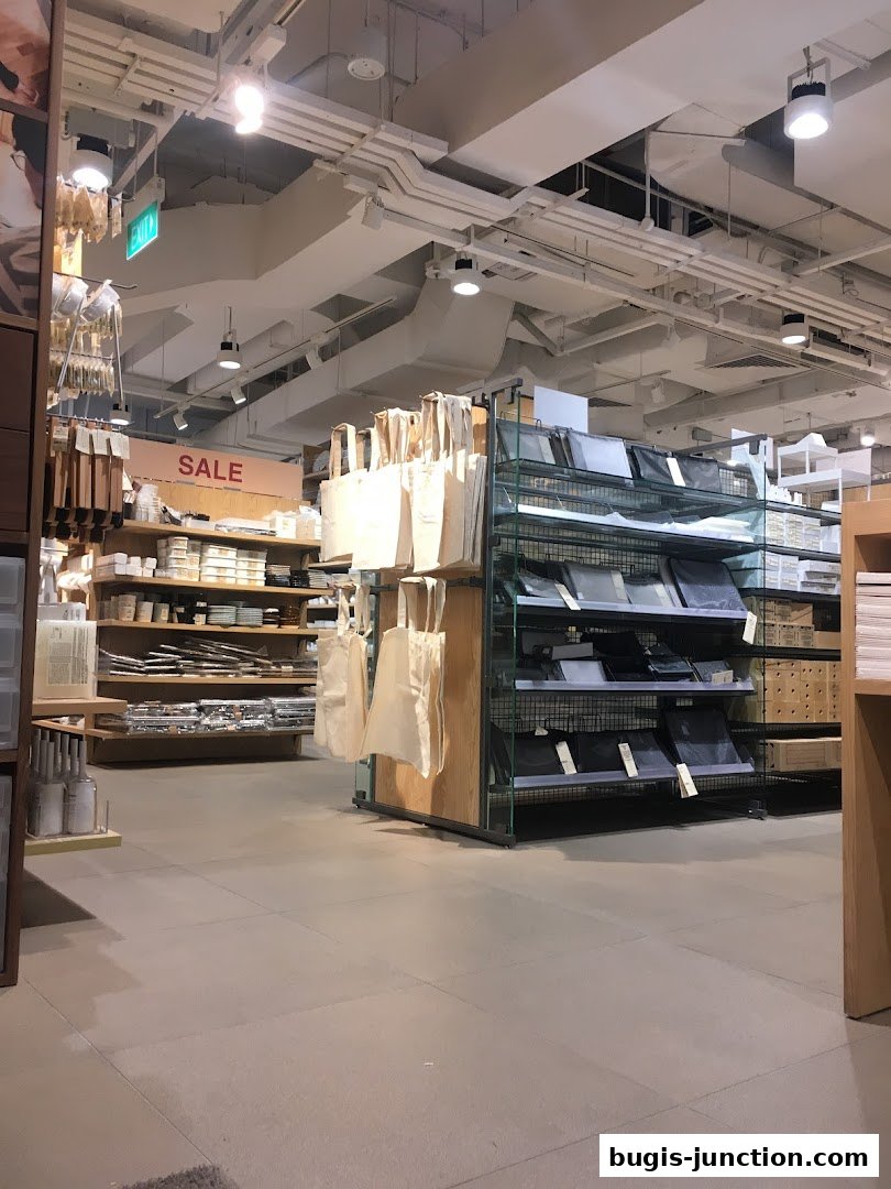 Interior view of a MUJI store showcasing shelves with various products and a prominent 'SALE' sign.