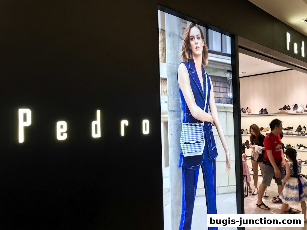 PEDRO store entrance with a fashion advertisement and shoppers inside.