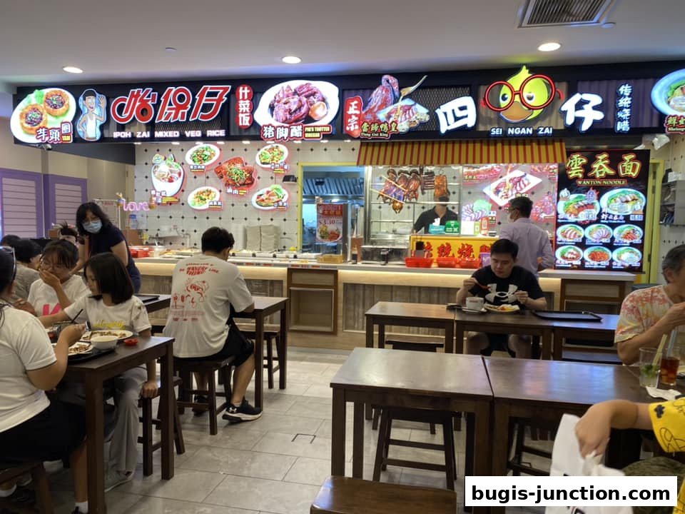 People eating at tables in a food court with bright signs displaying food.