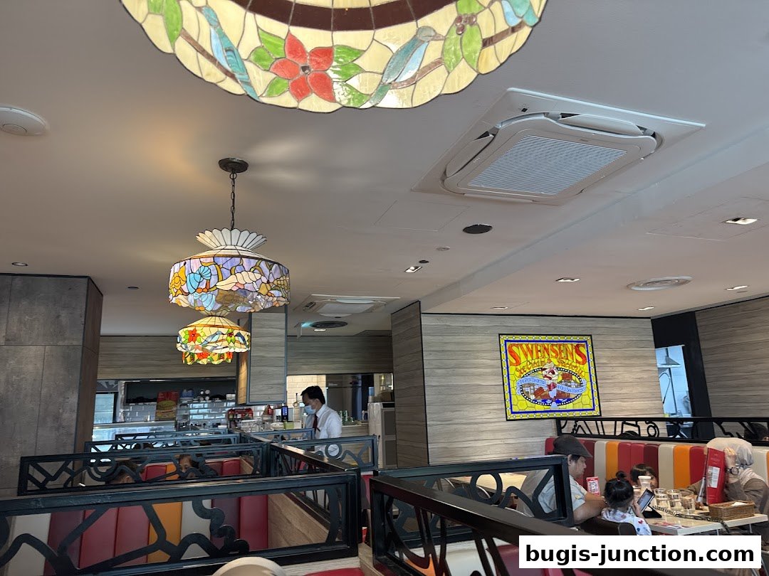 Interior view of Swensen's restaurant with stained glass lamps and diners.