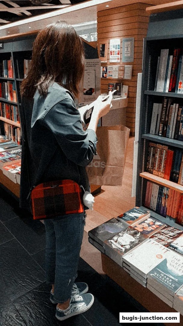 A person browsing books in a well-stocked bookstore with shelves full of titles.