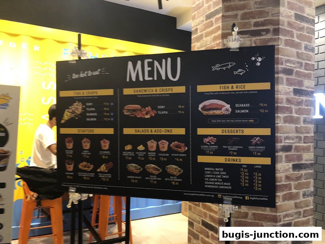 A menu board for Big Fish Small Fish featuring fish and crisps, sandwiches, fish and rice, desserts, and drinks.