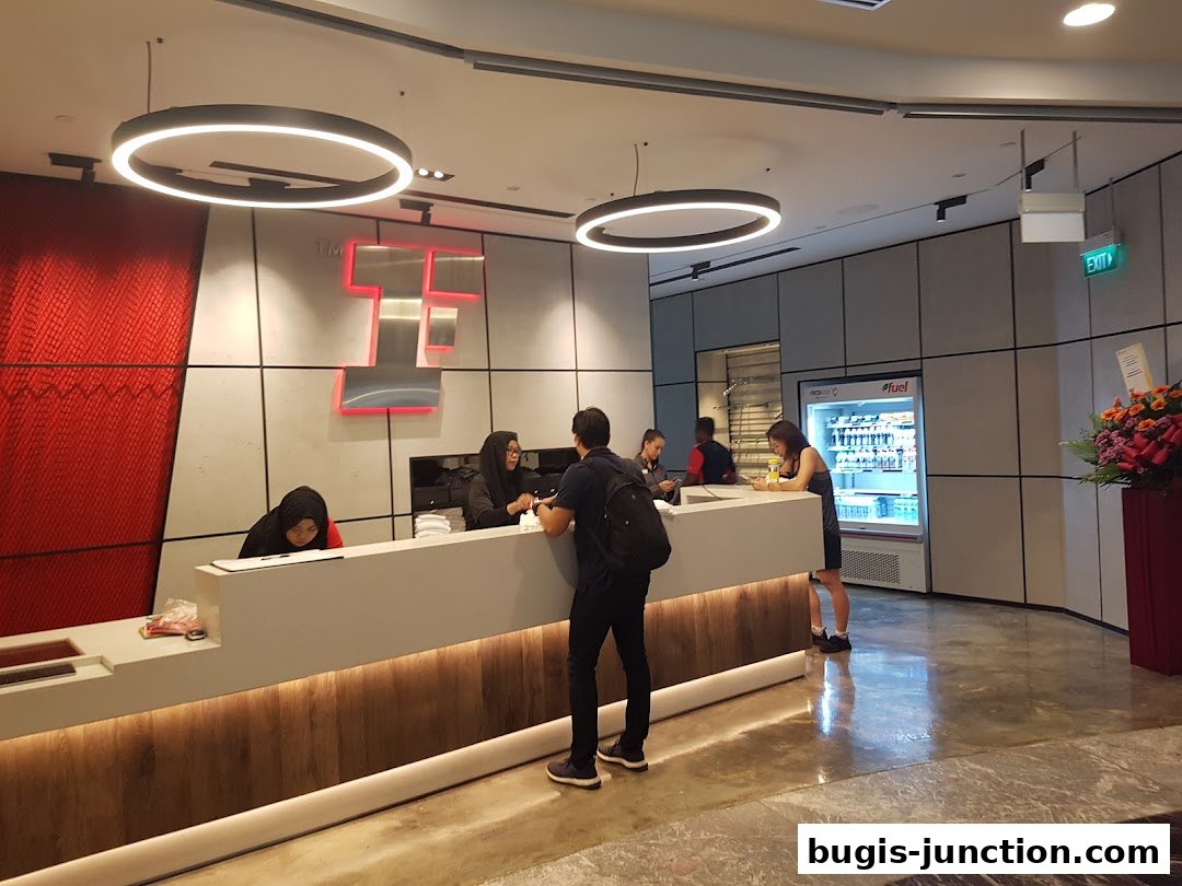 Reception area of a fitness center with staff and customers at the counter.