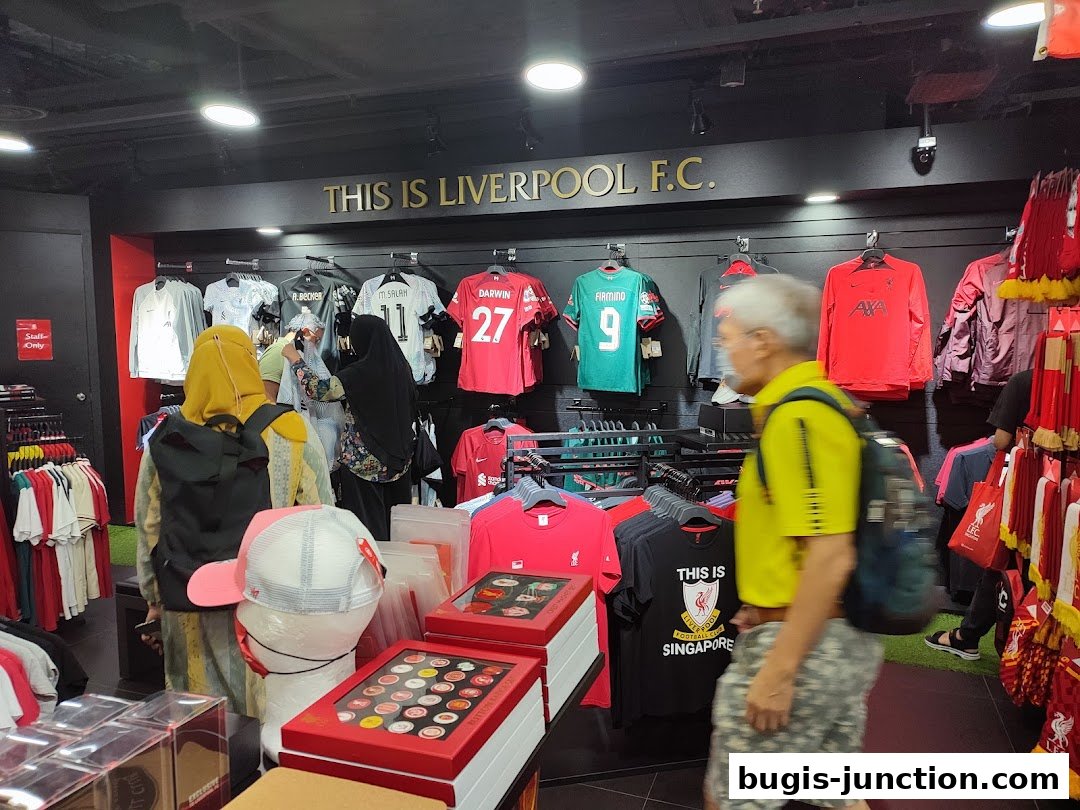 Interior of a Liverpool FC store with jerseys, apparel, and merchandise on display.