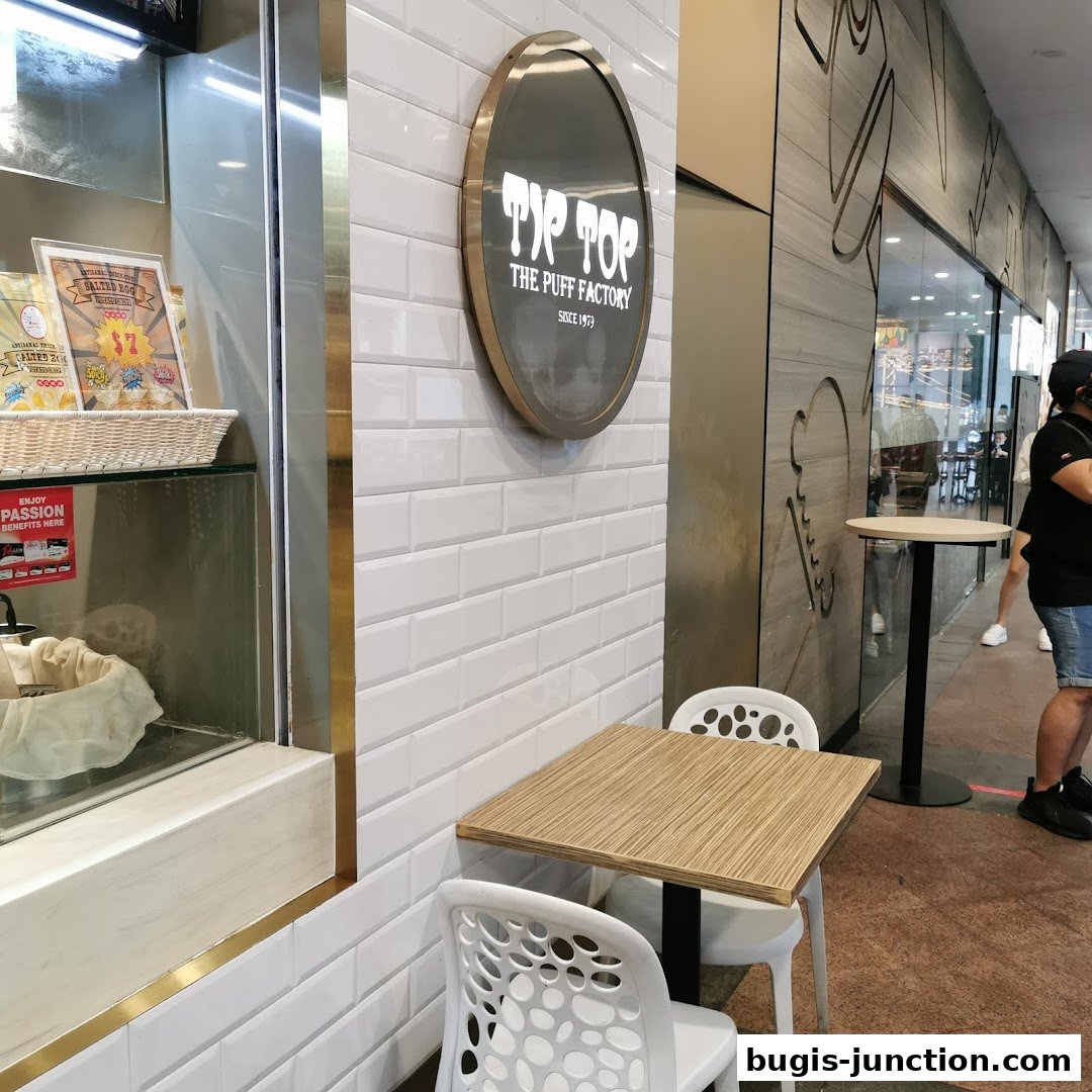 The exterior of Tip Top Curry Puff featuring a sign and seating area.