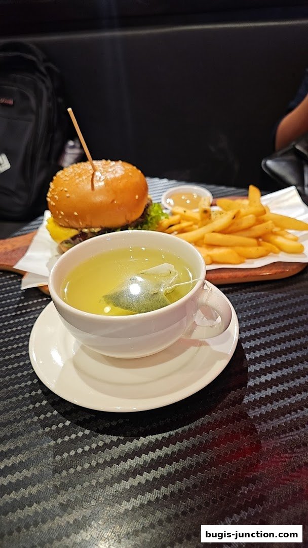 A delicious burger and fries meal served with a cup of green tea.